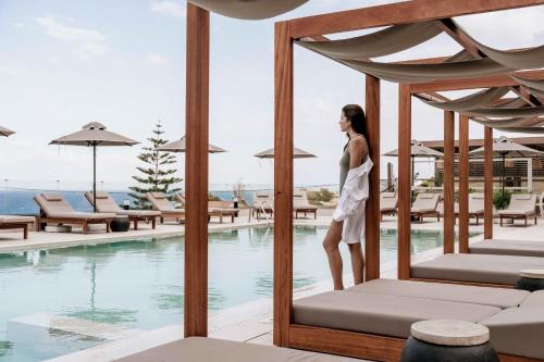 a woman standing on a bed next to a swimming pool at Irida Hotel Agia Pelagia in Agia Pelagia