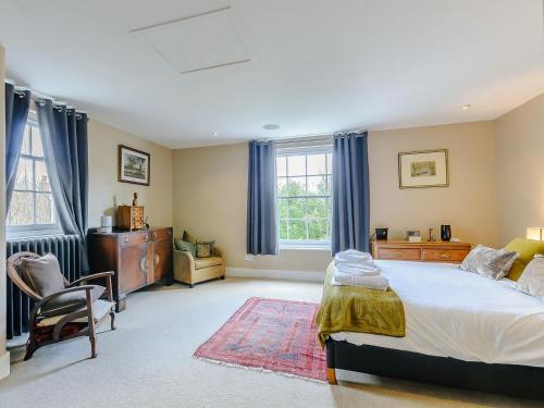 a bedroom with a bed and a chair and windows at Anchor Light Cottage in Faversham
