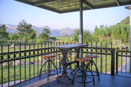 a table and stools on a deck with a view at Nex Station Kanchanaburi in Kanchanaburi