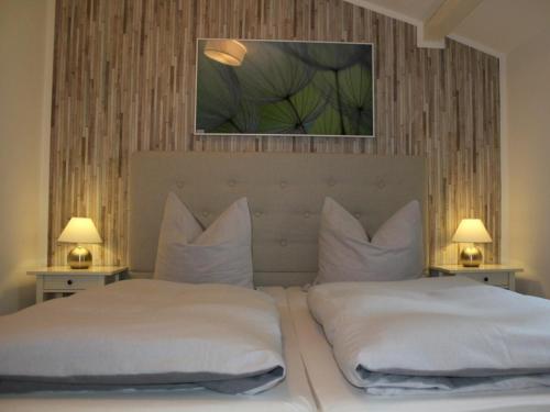 a bedroom with two beds with white sheets and two lamps at Chalet Heide in Winterberg