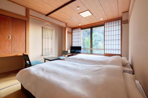 a bedroom with two beds and a window at Yukyo no Hibiki Yusai in Minamioguni