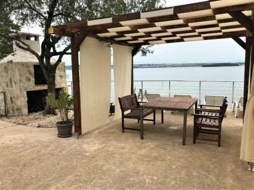 a wooden table and chairs under a wooden pergola at Seaside apartments Brist in Tkon