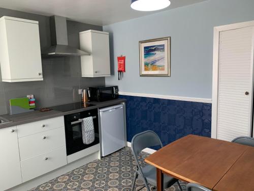 a kitchen with white cabinets and a table and a table and chairs at Squirrel Away At Leven House in Crieff