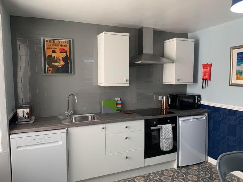 a kitchen with white cabinets and a sink at Squirrel Away At Leven House in Crieff