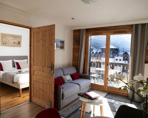 een woonkamer met een bank, een bed en een raam bij Mont Blanc 43, vue Mont Blanc , balcon, parking in Chamonix-Mont-Blanc