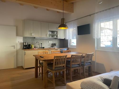 Il comprend une cuisine et une salle à manger avec une table et des chaises en bois. dans l'établissement Tuxie Haus, à Tux