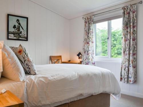 a bedroom with a white bed and a window at The Alpaca Lodge in Arlecdon