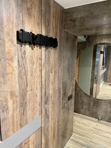 a bathroom with a wooden wall with a mirror at Siauliai ‘Four sisters’ in Šiauliai