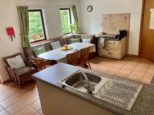 a kitchen with a sink and a table with chairs at Kingsmills Cottages in Artrea