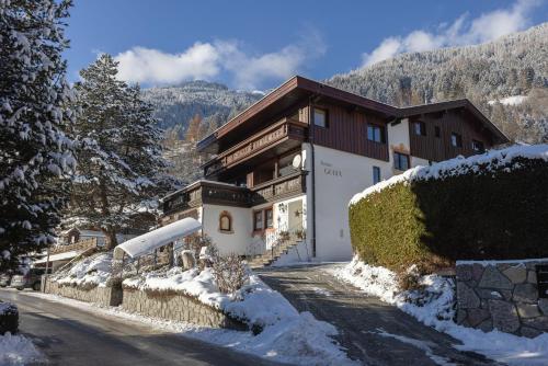 a house on a snow covered road in front of a mountain at Pension Gulla - Ferienhaus Appartements B&B in Neustift im Stubaital