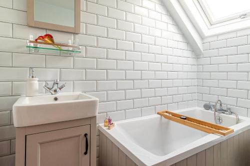 a white bathroom with a sink and a tub at Garth Cottage in West Ayton in Scarborough
