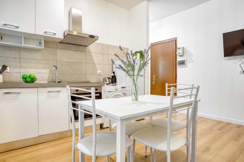 a white kitchen with a white table and chairs at ALTIDO Warm and Inviting flat with balcony in Milan