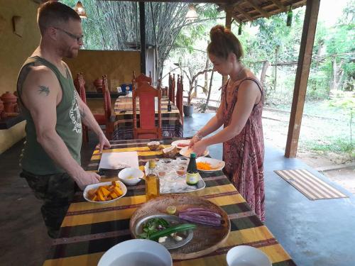 a man and a woman preparing food at a table at Sandalwood Cottage in Udawalawe