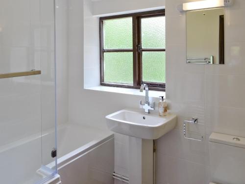 a white bathroom with a sink and a shower at The Granary in Knapton