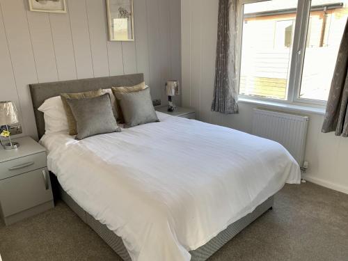 a bedroom with a large white bed with a window at Cherry Blossom 43 Hot Tub in Garton