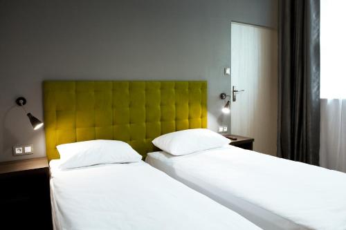 two beds in a bedroom with a green headboard at Pokoje Gościnne Tessa in Chełm