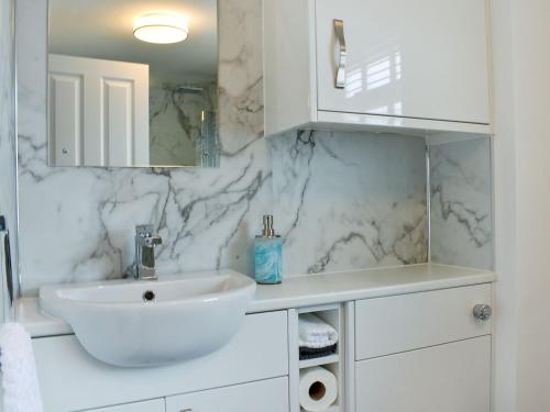 a white bathroom with a sink and a mirror at Riverside in Mevagissey