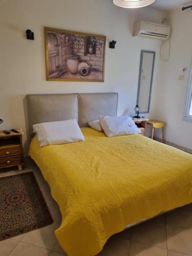 1 cama con edredón amarillo en un dormitorio en סוויטת פינת השקד en Rosh Pinna