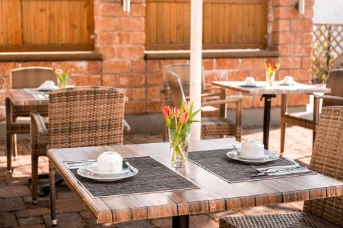 einen Holztisch mit Tellern und Blumen auf einer Terrasse in der Unterkunft Frühstückspension Christinenhof in Dreieich