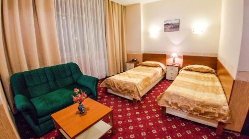 a hotel room with two beds and a green couch at Reikartz Dostar Karaganda in Karagandy