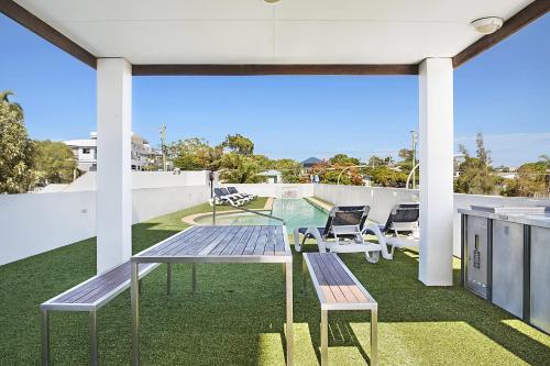 a patio with a table and chairs on a roof at Scarborough Beach Resort Brisbane in Scarborough