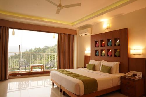 a bedroom with a large bed and a large window at The Fog Munnar (Resort & Spa) in Munnar