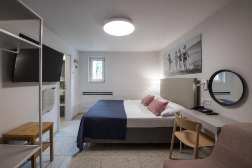 a bedroom with a bed and a desk and a mirror at Holiday Park Vile - Terme Krka in Strunjan