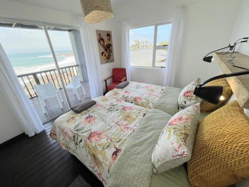 1 dormitorio con cama y vistas a la playa en Mazeppa Sunrise Beach Accommodation, en Mazeppa Bay