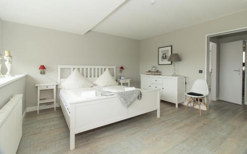 - une chambre blanche avec un lit et un bureau dans l'établissement Heefkant, à Sankt Peter-Ording
