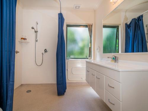 a bathroom with a shower and a sink at Pohutukawa on Paku - Tairua Holiday Home in Tairua