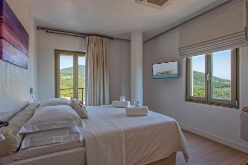 a bedroom with a large white bed with a window at Stargaze Villas in Panormos Skopelos