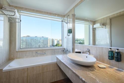 baño con lavabo, bañera y ventana en Melia Lisboa Oriente Hotel en Lisboa