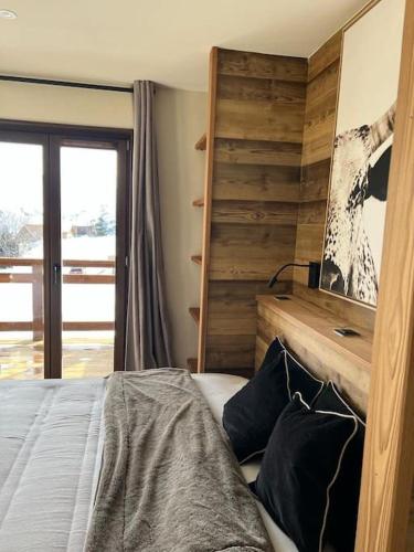 une chambre avec un lit et un mur en bois dans l'établissement Magnifique chalet sur les pistes, le Paradis c'est ici !, à La Toussuire