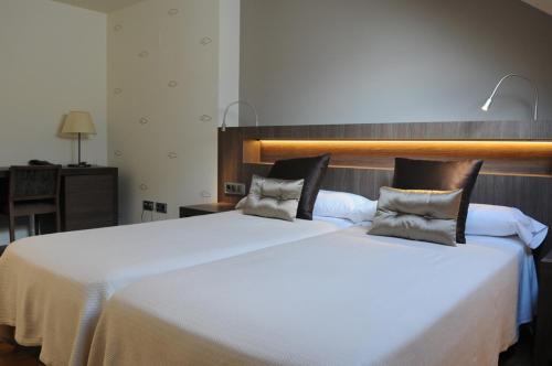 a large white bed with two pillows on it at Albergue Guiana in Ponferrada