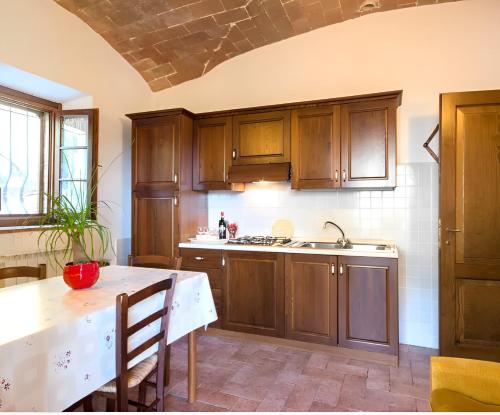 a kitchen with wooden cabinets and a white table at Agriturismo Casale Giulia in Volterra
