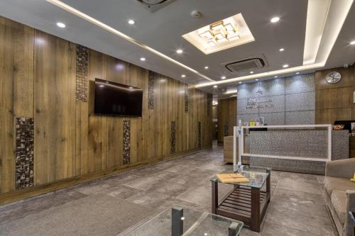 a lobby with wooden walls and a tv on the wall at Hotel Sifat International in Surat