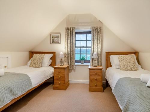 two beds in a attic room with a window at The Old Combine Shed in Huby