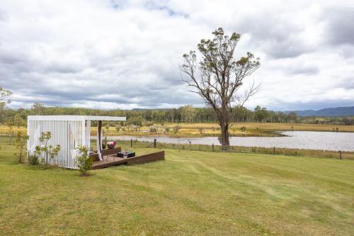 a small shed in a field next to a lake at Soulful Grande Manor with Mineral Pool in Millfield