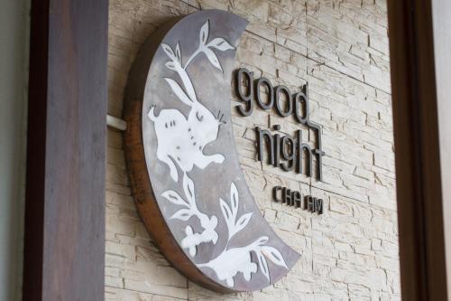 a sign on the side of a building with a clock at Goodnight Cha Am Minitel in Cha Am