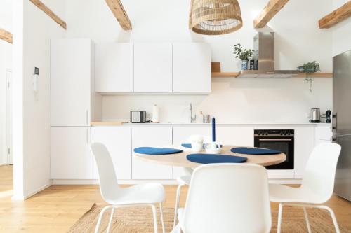 a white kitchen with a wooden table and white chairs at Beautiful Penthouse - City Center in Graz