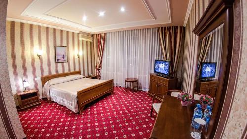 Reikartz Dostar Karaganda في كاراغاندي: غرفه فندقيه سرير وتلفزيون