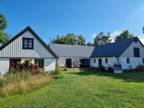 a white barn with a black roof and a yard at 4B Österlen Bed & Breakfast in Tomelilla