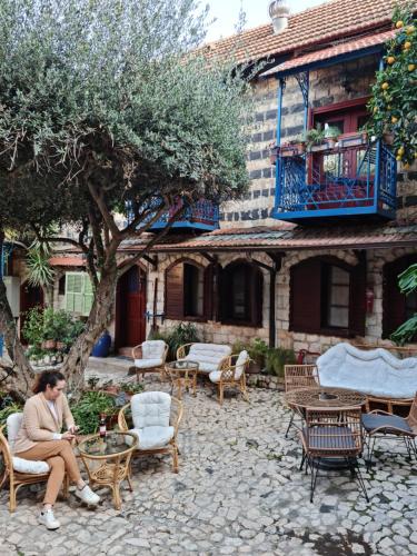 a woman sitting in a chair in front of a building at וילה תהילה המחודש - The new Villa Tehila in Rosh Pinna