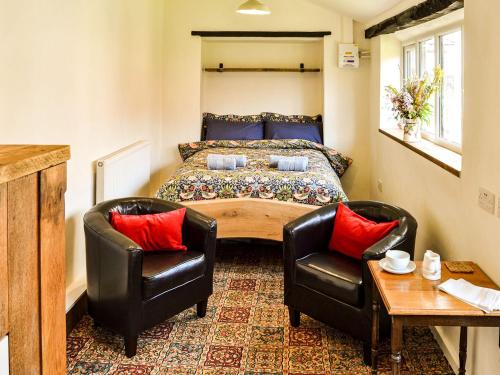 a bedroom with a bed and two chairs at The Bothy in Hockham