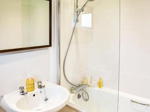 ein weißes Bad mit einem Waschbecken und einer Dusche in der Unterkunft The Bothy in Hockham