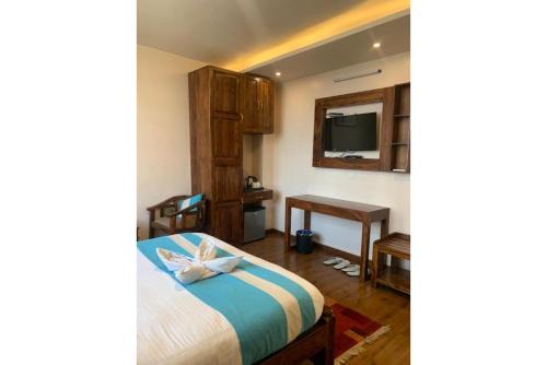 1 dormitorio con 1 cama, escritorio y TV en Hotel Tapas, en Katmandú