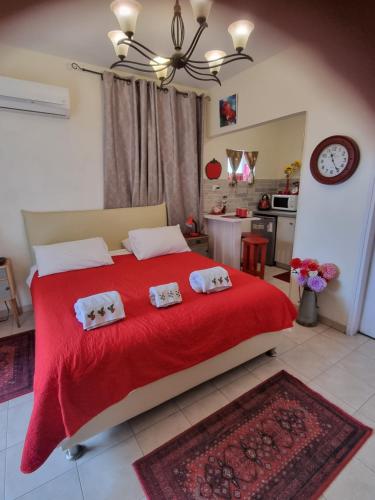1 dormitorio con 1 cama roja y 2 toallas en Pinat Hashaked, en Rosh Pina