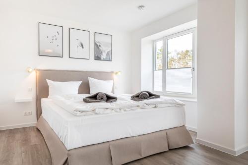 ein weißes Schlafzimmer mit einem großen Bett und einem Fenster in der Unterkunft Ferienwohnung Sonnenschein Haus Hiddensee Prora in Binz
