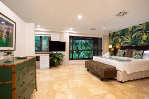 a bedroom with a large bed and a television at NYARU Villa Port Douglas, QLD in Port Douglas