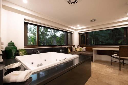 una gran bañera blanca en una habitación con ventanas en NYARU Villa Port Douglas, QLD, en Port Douglas